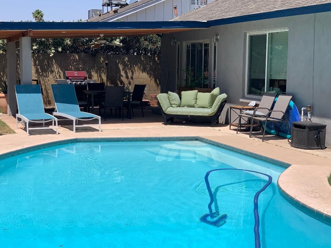 A swimming pool with lounge chairs and a covered patio area.