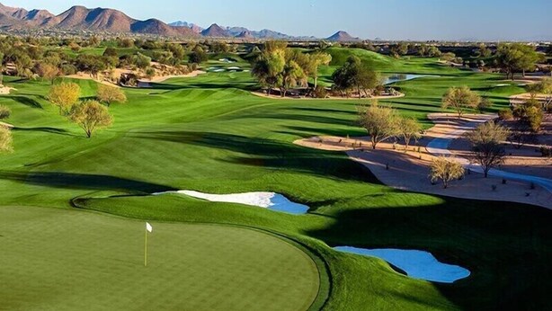 Un campo de golf con una bandera, búnkeres de arena y un obstáculo acuático.