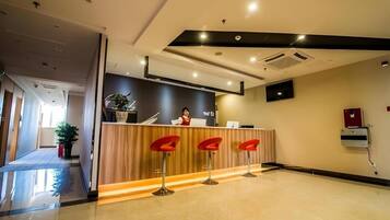 A reception area with a receptionist, a counter, and three red bar stools.