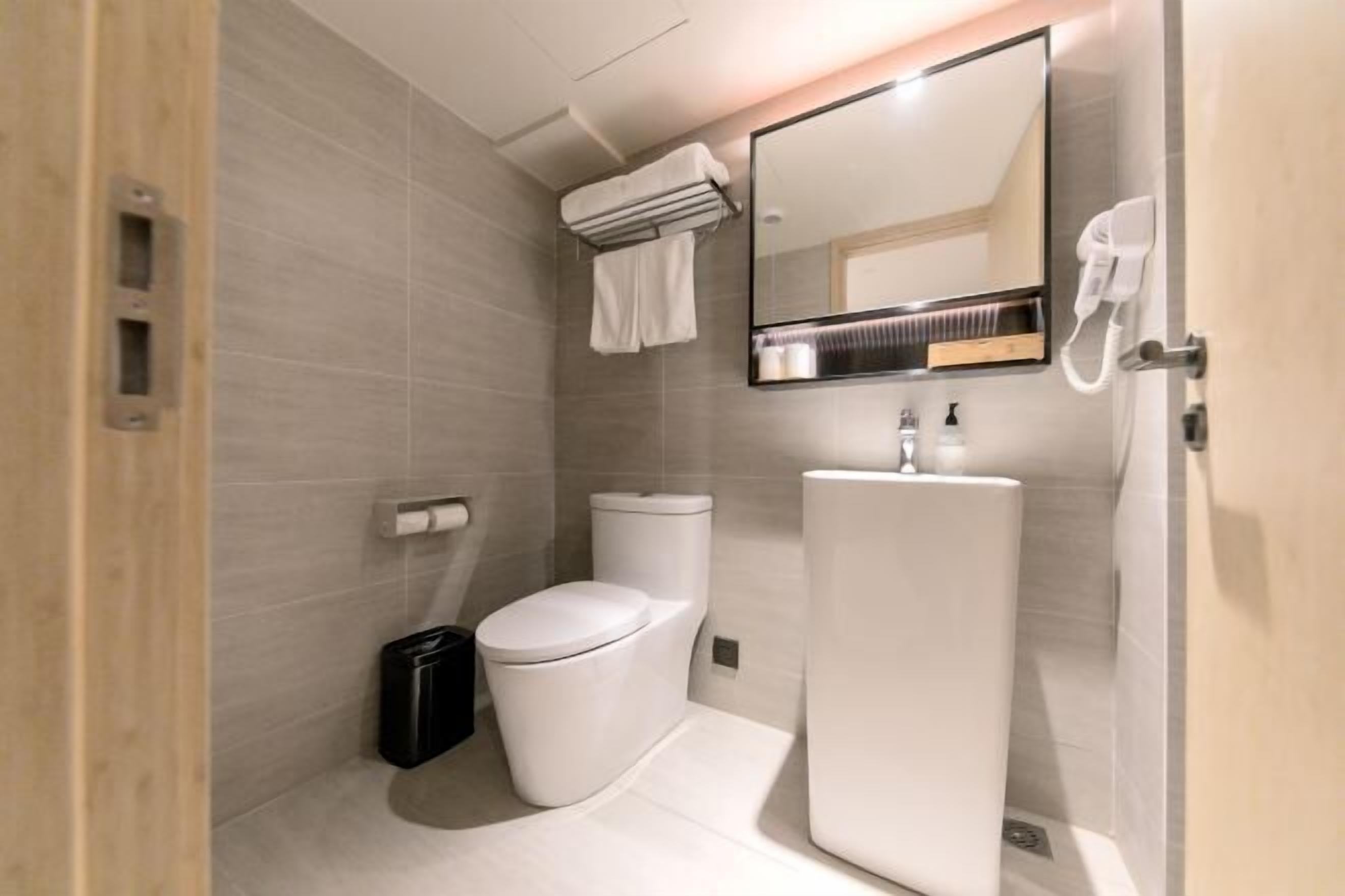 Une salle de bain moderne avec des toilettes, un lavabo et un miroir.
