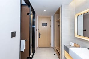 A modern hotel hallway with a wooden door, a glass door, a vanity with a mirror, and a towel rack. - Ji Hotel (Shanghai)