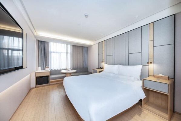 A modern hotel room with a large bed, bedside tables, a seating area, and a large window with curtains. - Ji Hotel (Shanghai)
