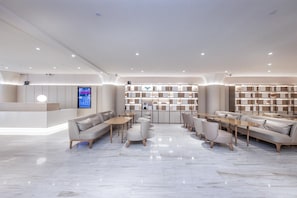 A modern hotel lobby with a reception desk, seating areas, and a large bookshelf. - Ji Hotel (Shanghai)