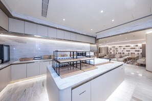 A modern kitchen with a central island, built-in cabinets, and a dining area with seating. - Ji Hotel (Shanghai)