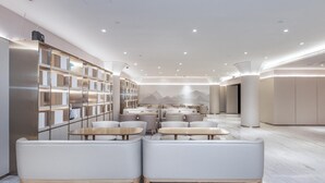 A modern interior with seating areas, a bookshelf, and a mural on the wall. - Ji Hotel (Shanghai)