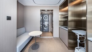 A modern hotel room with a built-in washer and dryer, a seating area, and a small table. - Ji Hotel (Shanghai)