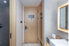 A modern bathroom with a wooden door, a sink, and a mirror. - Ji Hotel (Shanghai)