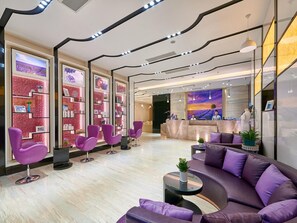 Ein modernes Interieur mit violetten Sitzgelegenheiten, einer Rezeption und einer großen Wand mit Kunstwerken.
