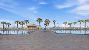 A poolside area with a bar, palm trees, and a clear sky. - The Summit 306-Beachfront Getaway on the 3rd Floor (Panama City)