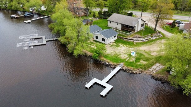 A lakeside property with a dock, a house, and a boat. - Waterfront home (Pelican Lake)