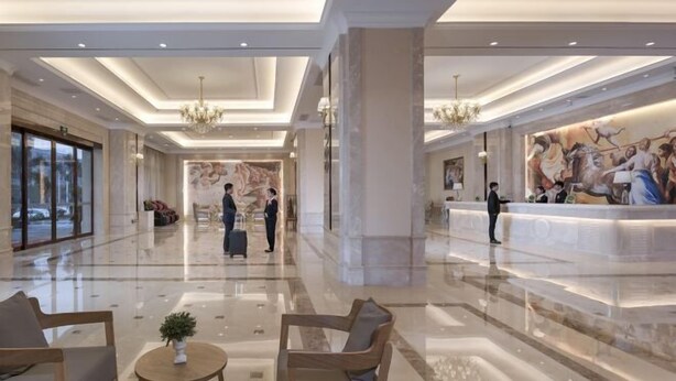 A spacious lobby with a marble floor, wooden furniture, and a reception desk. - Vienna International Hotel (Danzhou Dingshang Square) (Danzhou)