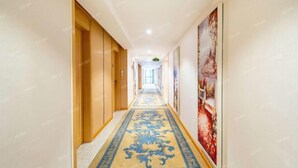 A hallway with a patterned carpet, wooden doors, and a large framed picture on the wall. - Vienna International Hotel (Danzhou Dingshang Square) (Danzhou)