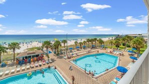 Ein Poolbereich mit zwei Schwimmbecken, einem Strand und einer Bar.