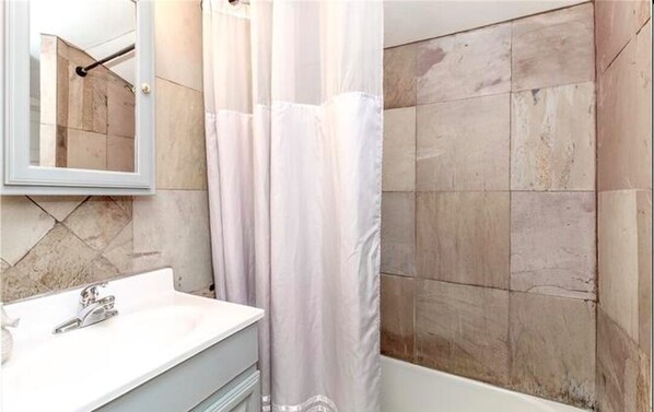Une salle de bain avec un lavabo blanc, un miroir et un rideau de douche.