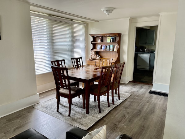 Un comedor con una mesa y sillas de madera, un tapete y una estantería.