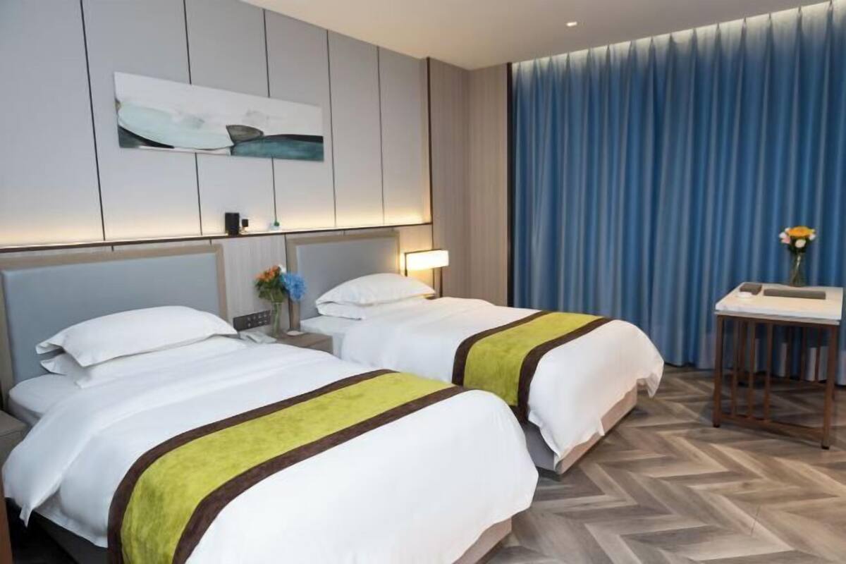 Habitación de hotel con dos camas, un escritorio y una silla.