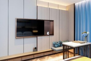 Una sala de estar moderna con una televisión de pantalla plana montada en la pared, un sofá con cojines, una mesita con un jarrón de flores y un banco de madera.
