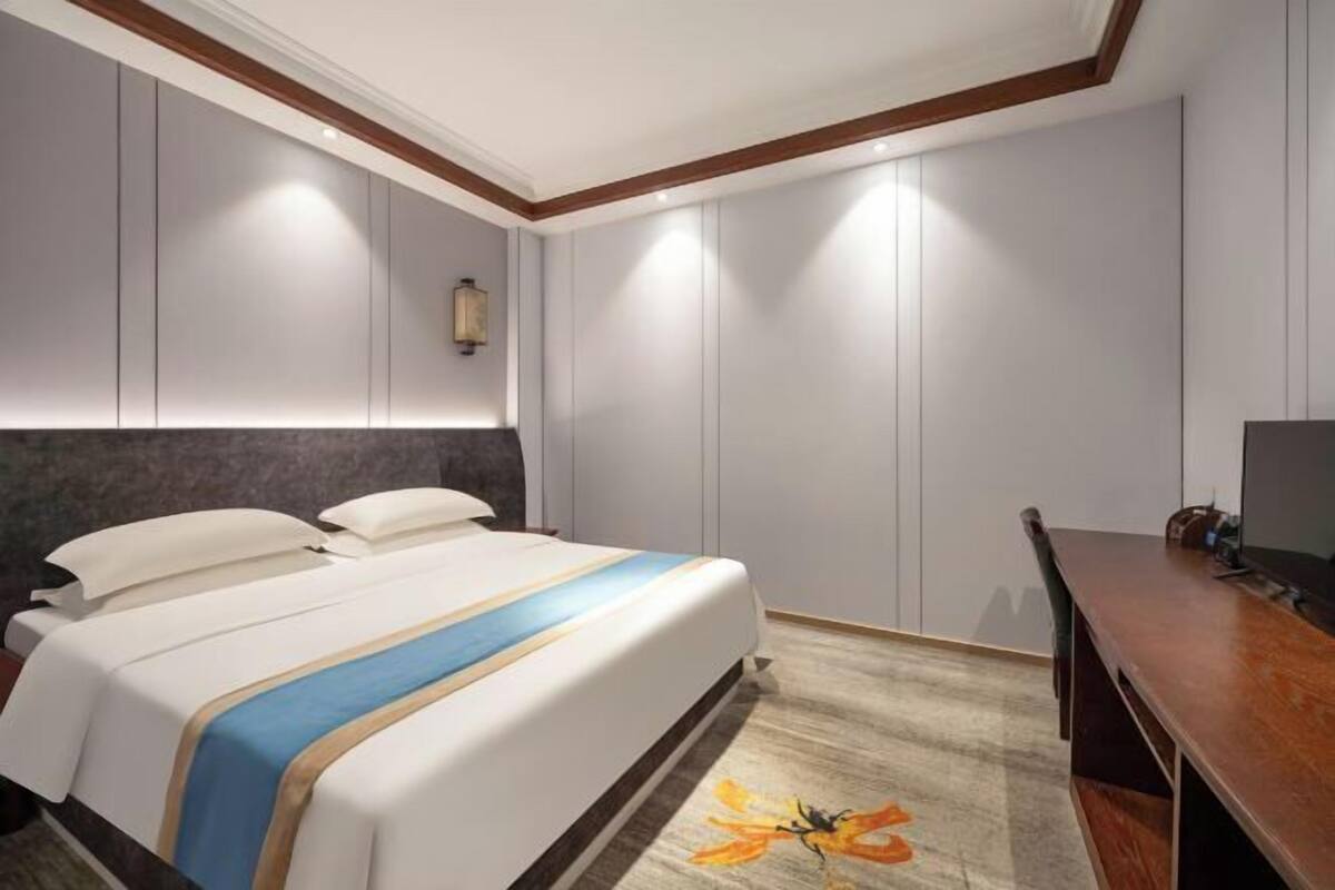 Una habitación de hotel con una cama, un escritorio y una lámpara fijada a la pared.