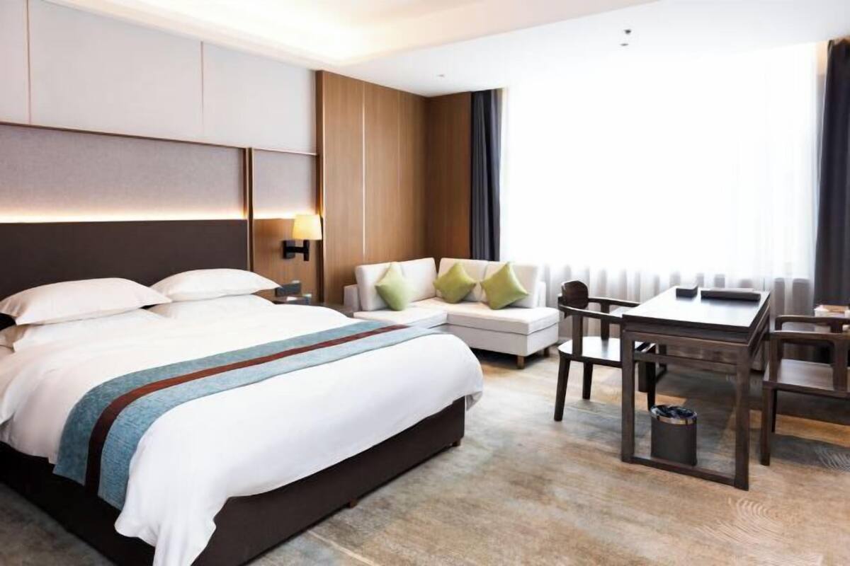 Una habitación de hotel con cama, sofá, escritorio y silla.