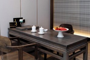 A modern dining area with a dark wooden table, white serving dishes, and a fruit plate. - Hekou Hotel (Dongying)