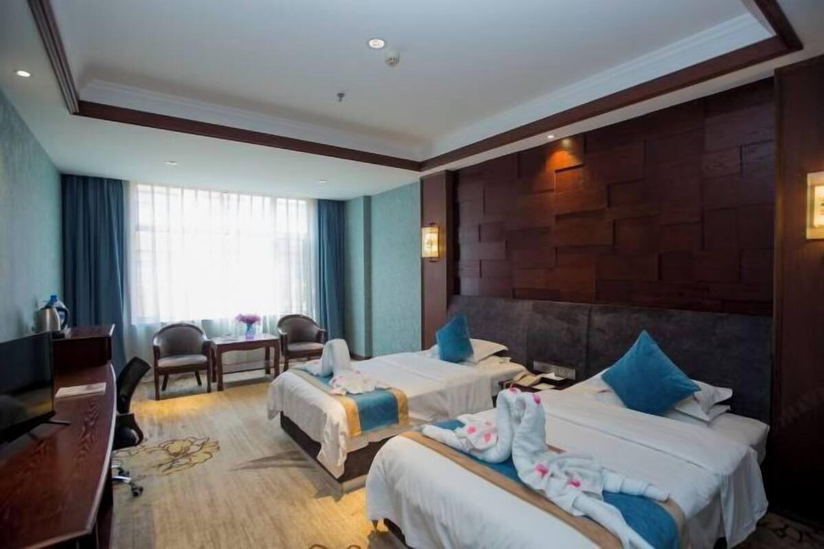 Una habitación de hotel con dos camas, un escritorio, una silla y un televisor.