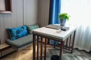 A room with a sofa, a table with a laptop, a plant, and a window with curtains. - Hekou Hotel (Dongying)