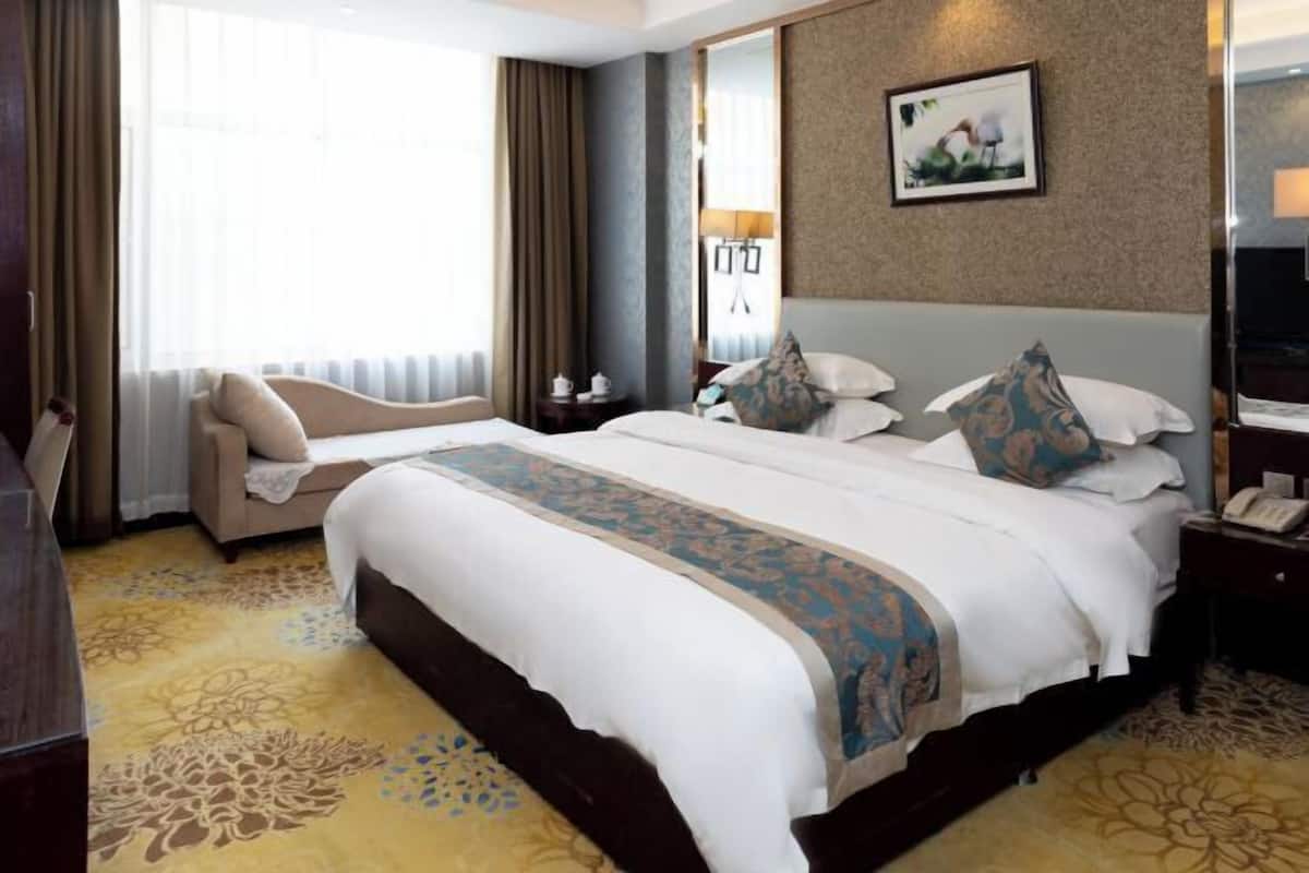 Habitación de hotel con una cama grande, un sofá, un escritorio y un espejo.