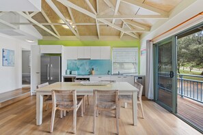 A modern kitchen with a central island, white cabinetry, and a view to the outdoors.