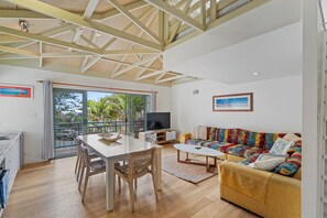 A spacious living area with a dining table, sofa, and television.