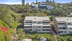 A modern multi-story residential building with a swimming pool and outdoor seating area. - The Cove - Jewel by the Sea (Point Lookout)