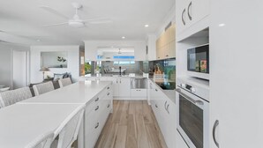A modern kitchen with white cabinetry, a central island, and a built-in oven. - The Cove - Jewel by the Sea (Point Lookout)
