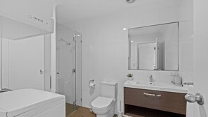 Un baño moderno con ducha, inodoro y tocador.