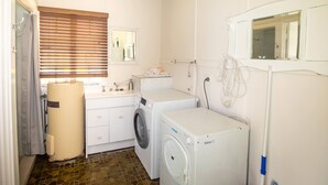 A compact laundry room with a washing machine, dryer, and a small sink. - Cabana - One of the only original Straddie beach shacks left standing. (Point Lookout)
