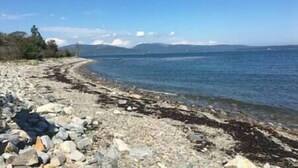 Un rivage rocheux bordé d’une eau claire, avec des montagnes qui se dessinent à l’horizon.