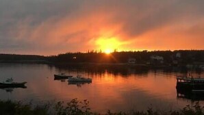 Un coucher de soleil sur un lac paisible, avec des bateaux et un quai.