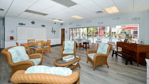 Une pièce spacieuse, meublée de mobilier en osier, avec une table à manger et une vue sur l’espace piscine.
