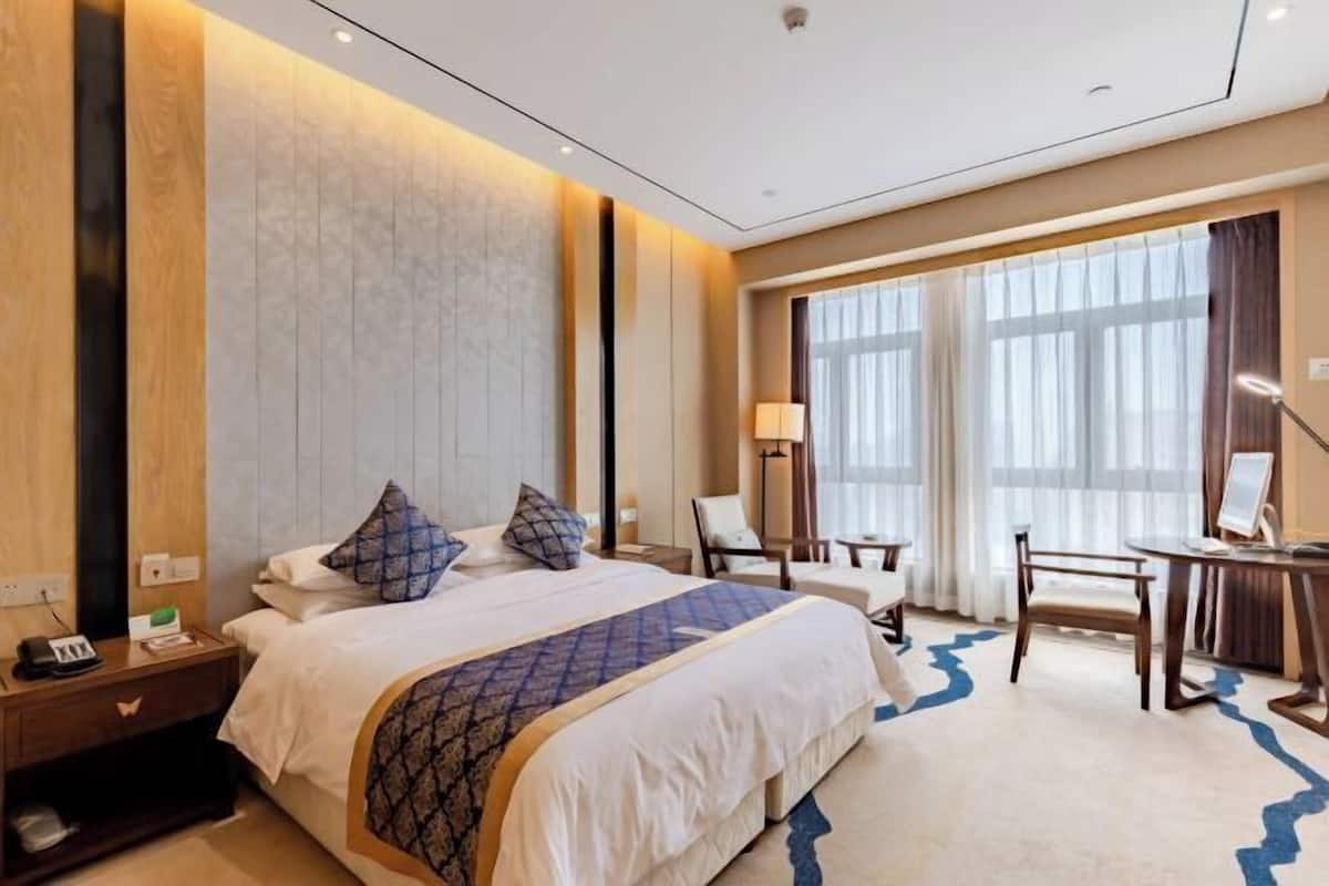 Une chambre d’hôtel avec un grand lit, un bureau et une chaise.