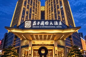 Exterior del Hotel Zhuang Zi International, con una entrada destacada y señalización iluminada.