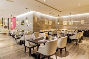 Un restaurante moderno con varias mesas y sillas, y un diseño de interiores limpio y contemporáneo.