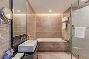 Un baño moderno con un espejo grande, un lavamanos rectangular y una bañera independiente.