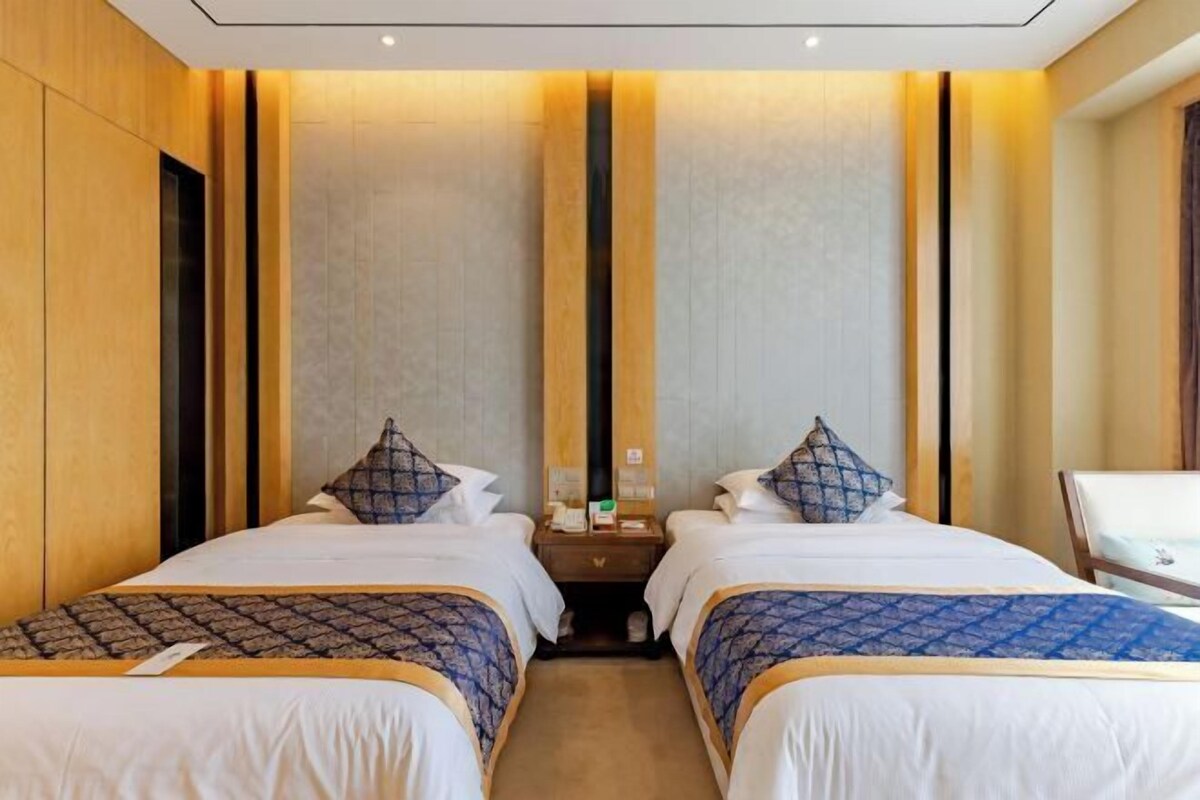 A hotel room with two beds, a nightstand, and a mirror.