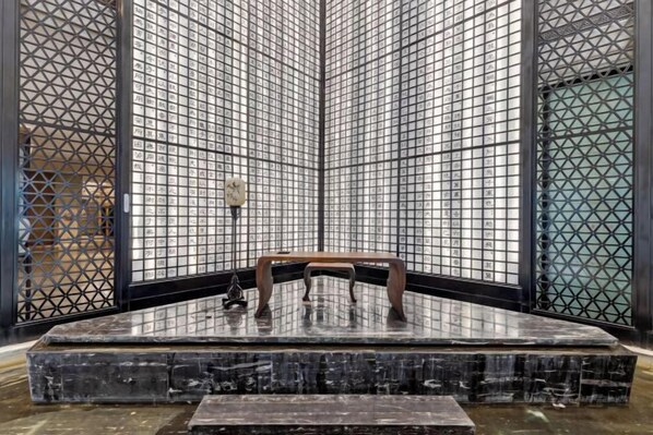 A room with a tiled wall, a wooden bench, and a small table. - Zhuangzi International Hotel (Mengcheng)