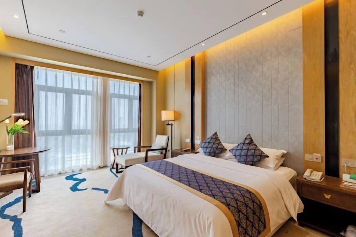 Une chambre d’hôtel avec un grand lit, des tables de chevet, un bureau et une chaise.