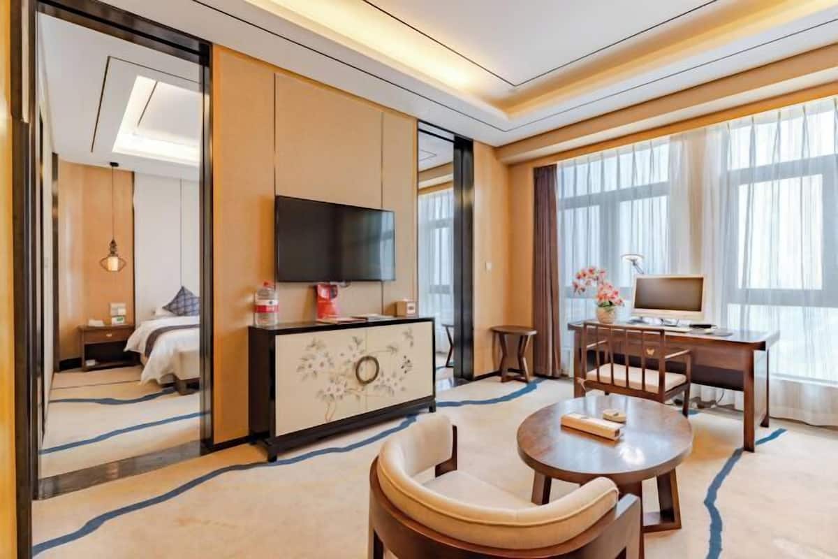 Une chambre d’hôtel équipée d’un lit, d’une télévision, d’un bureau avec un ordinateur et d’un coin repas avec des chaises.