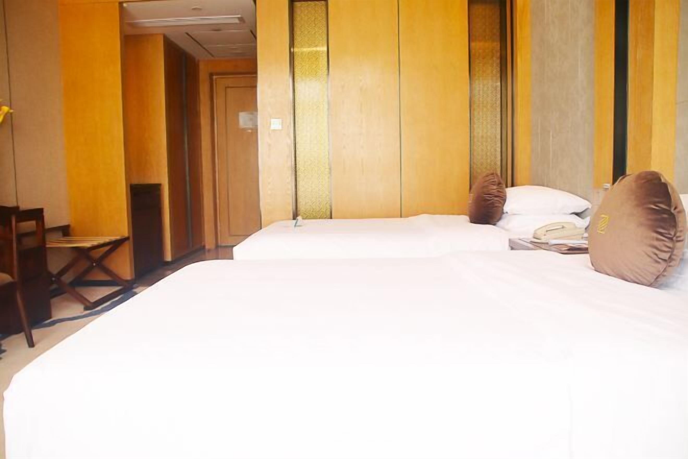 A hotel room with two beds, a desk, and a chair.