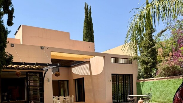Una casa moderna con piscina, un porche cubierto y un césped bien cuidado.