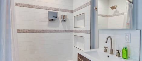 A modern bathroom with a bathtub, a sink with a mirror, and a shower area.