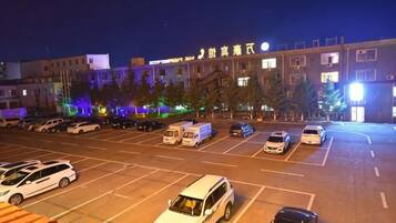 Un estacionamiento con varios autos y un edificio al fondo.