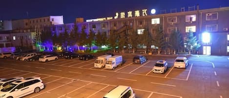 Un estacionamiento con varios autos y un edificio al fondo.