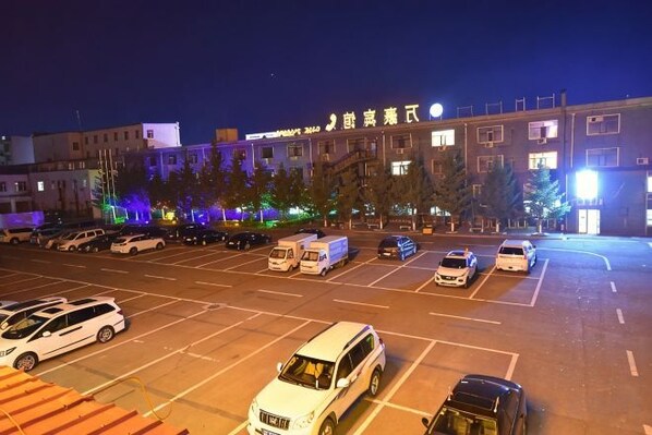A parking lot with multiple cars and a building in the background. - Wanhao Hotel (Hailun)